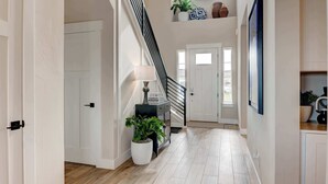 A spacious hallway with a staircase, a potted plant, and a lamp. - Spacious 4BR Retreat Near Bozeman (Belgrade)