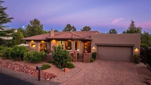 A two-story house with a tiled roof, a garage, and a landscaped front yard with a mailbox.