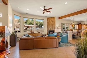 A spacious living area with a large sofa, a ceiling fan, and a fireplace. - Exquisite Retreat Salt Private Pool, Spa, Mtn View (Sedona)