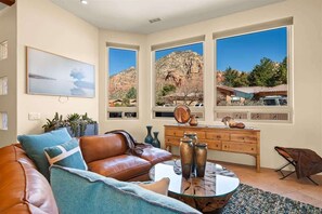 A living room with a leather couch, a glass coffee table, and a view of a mountain landscape through large windows. - Exquisite Retreat Salt Private Pool, Spa, Mtn View (Sedona)