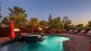 A backyard with a swimming pool, hot tub, and outdoor furniture.