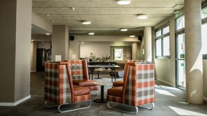 A spacious room with a high ceiling, concrete pillars, and a central table with chairs. - Prince Consort Village (London)
