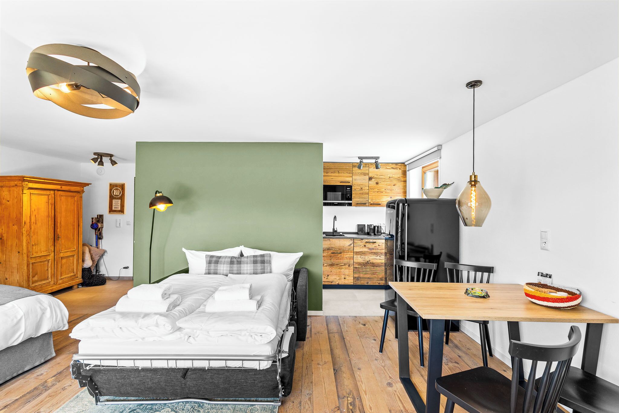 Une chambre à coucher moderne avec un lit, une table de chevet et un mur d’accent vert.