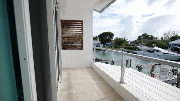A balcony with a view of a marina, a wooden shutter, and a tiled floor.