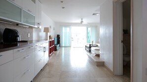 A modern kitchen with white cabinets, a coffee machine, and a dining area with a table and chairs.