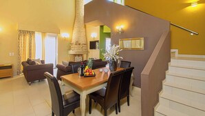 A dining area with a wooden table and chairs, a fruit basket, and a vase with flowers. - Amoena Villa - Theo Villas With Sea View (Marathokefala)