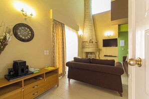 A living room with a sofa, a clock, a fireplace, and a television.