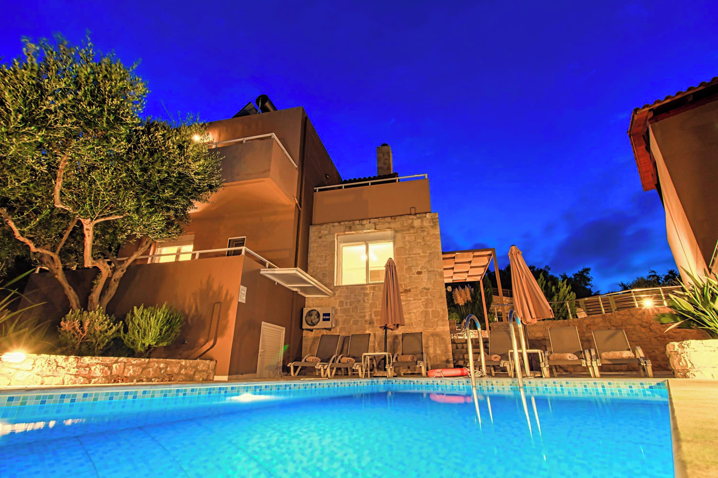 Ein Pool mit Liegestühlen, ein Steinhaus und ein Baum.