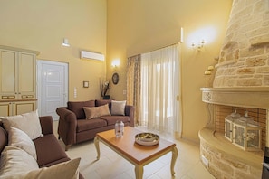 A living room with a sofa set, a coffee table with a decorative bowl, a stone fireplace with birdcages, and a door with a light switch.