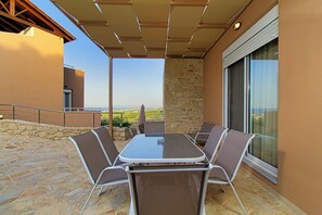 A patio with a table and chairs, a stone wall, and a view of the landscape.