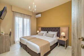 Een hotelkamer met een groot bed, nachtkastjes, een televisie en een kroonluchter.