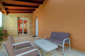 An outdoor patio with a stone wall, a wooden ceiling, and a table with two chairs. - Rose Villa - Theo Villas With Sea View (Marathokefala)