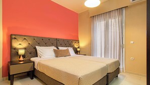 Een tweepersoonsbed met een gestoffeerd hoofdbord, twee nachtkastjes met lampen, een groot raam met gordijnen en een airconditioner aan de muur.