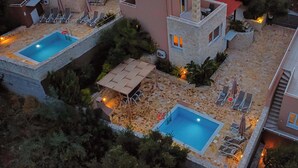 Un complexe résidentiel doté de deux piscines, d’espaces de détente en plein air et d’une terrasse en pierre.