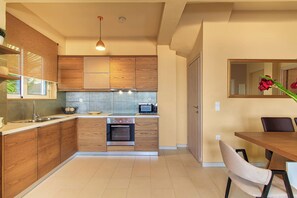 A modern kitchen with wooden cabinets, a built-in oven, a sink, and a dining area with a table and chairs.