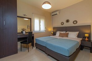 Een slaapkamer met een tweepersoonsbed, een bureau met stoel, een raam met zonwering en een wandairconditioning.
