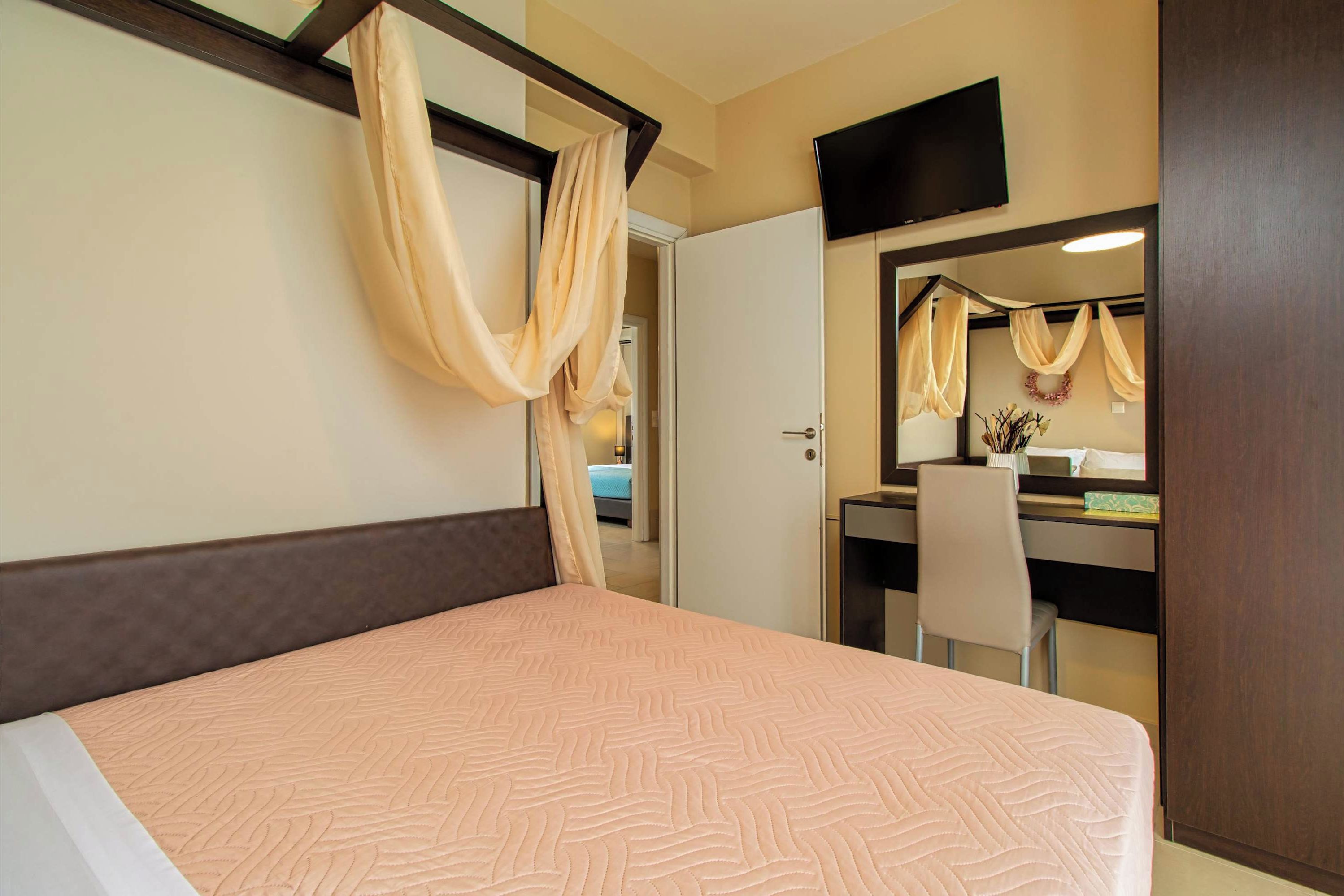 Ein Hotelzimmer mit Bett, Schreibtisch, Stuhl, Fernseher und Kleiderschrank.