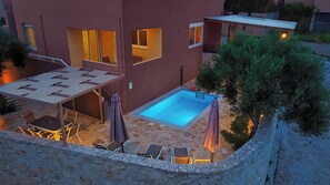 Un edificio moderno con piscina, zona de estar al aire libre y pared de piedra.