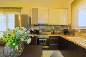A modern kitchen with dark cabinetry, stainless steel appliances, and a wooden countertop. - Lillium Villa - Theo Villas With Sea View (Marathokefala)