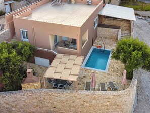A modern building with a swimming pool, outdoor seating, and a stone wall. - Lillium Villa - Theo Villas With Sea View (Marathokefala)