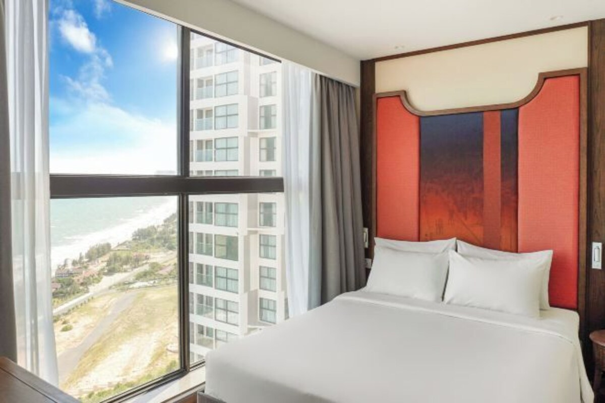 A hotel room with a large window offering a view of buildings and a landscape.