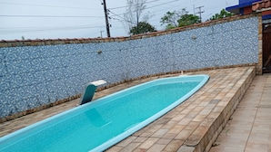 Una piscina rectangular con un muro y un borde empedrado.