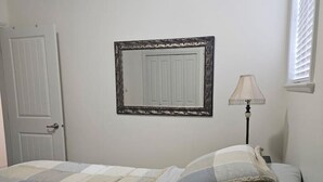 Een slaapkamer met een bed, een deur, een lamp en een raam.