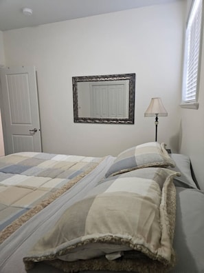 Un dormitorio con cama, puerta, lámpara y ventana.
