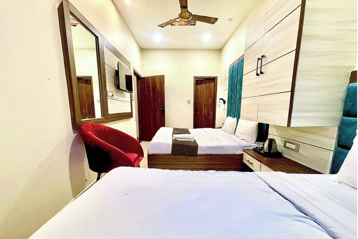 Una habitación de hotel con dos camas, una silla roja, un ventilador de techo y muebles de madera.