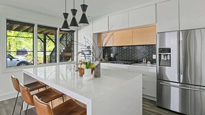 A modern kitchen with a central island, stainless steel appliances, and large windows. - Le Venture (Atlanta)