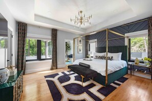 Une chambre moderne avec un lit à baldaquin, une grande fenêtre et un lustre.