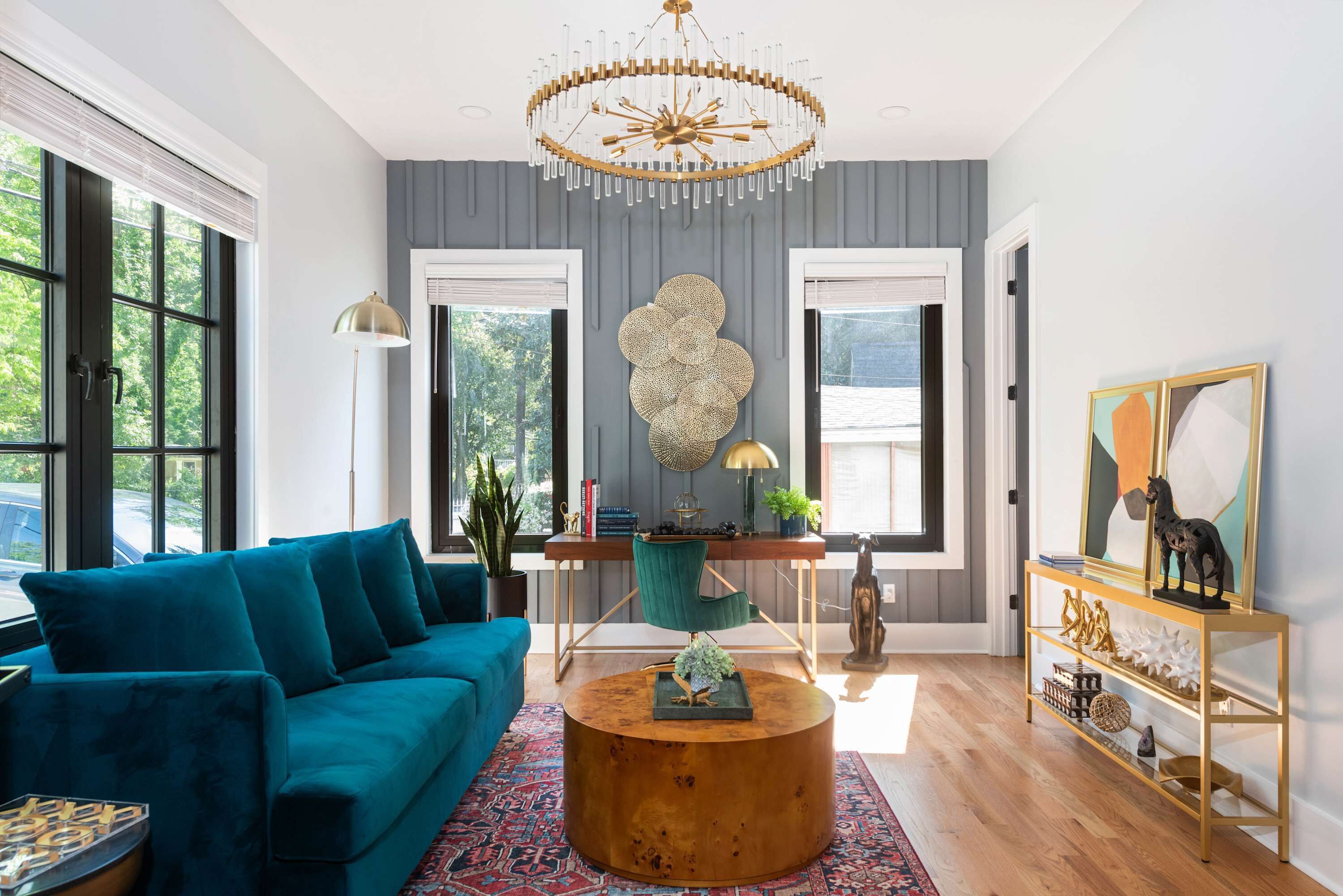 Un salon moderne avec un canapé de couleur turquoise, une table basse ronde en bois et un élément décoratif mural.