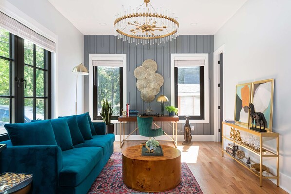 Un salon moderne avec un canapé de couleur turquoise, une table basse ronde en bois et un élément décoratif mural.