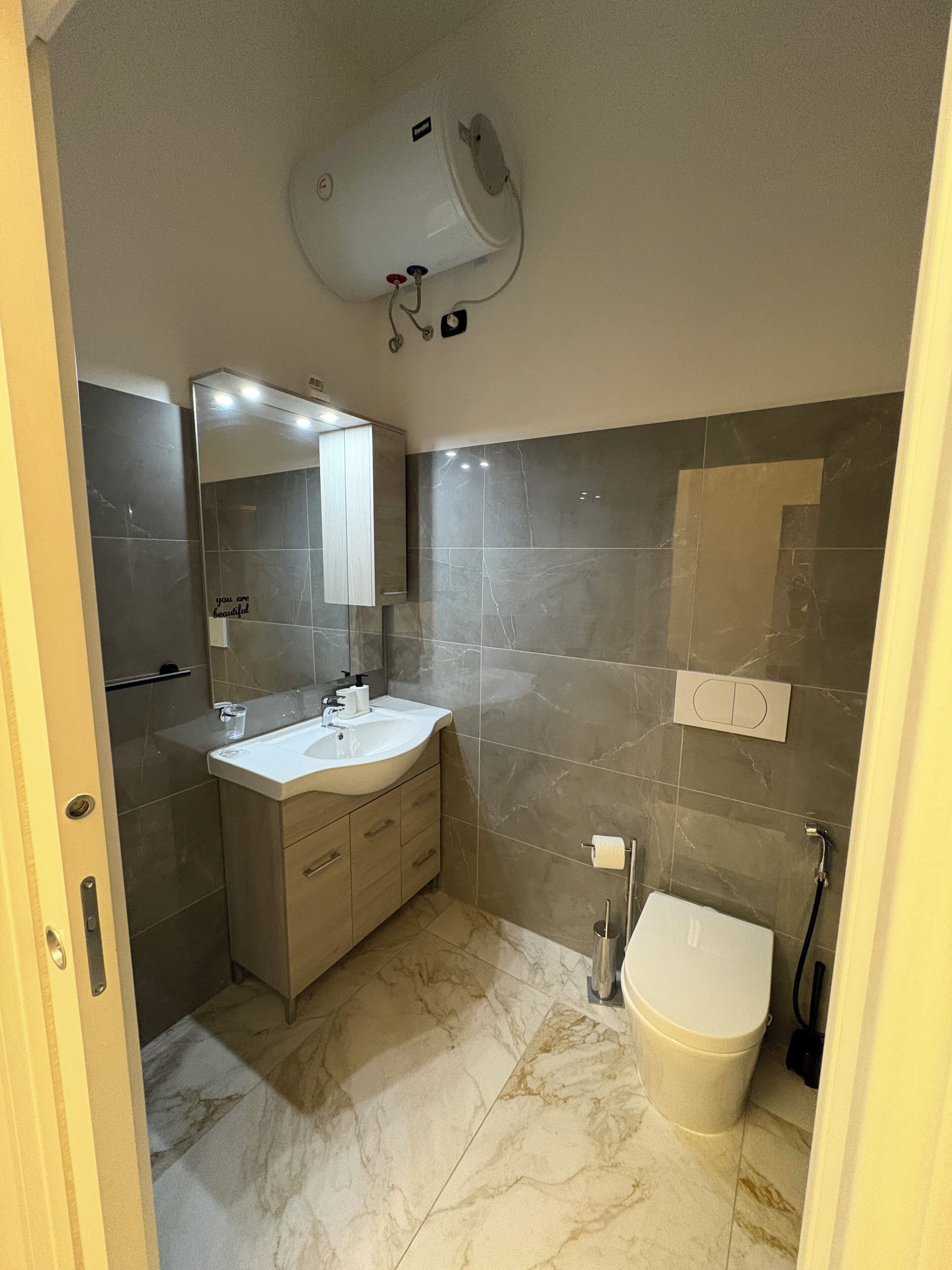 A bathroom with a white sink, mirror, and toilet.