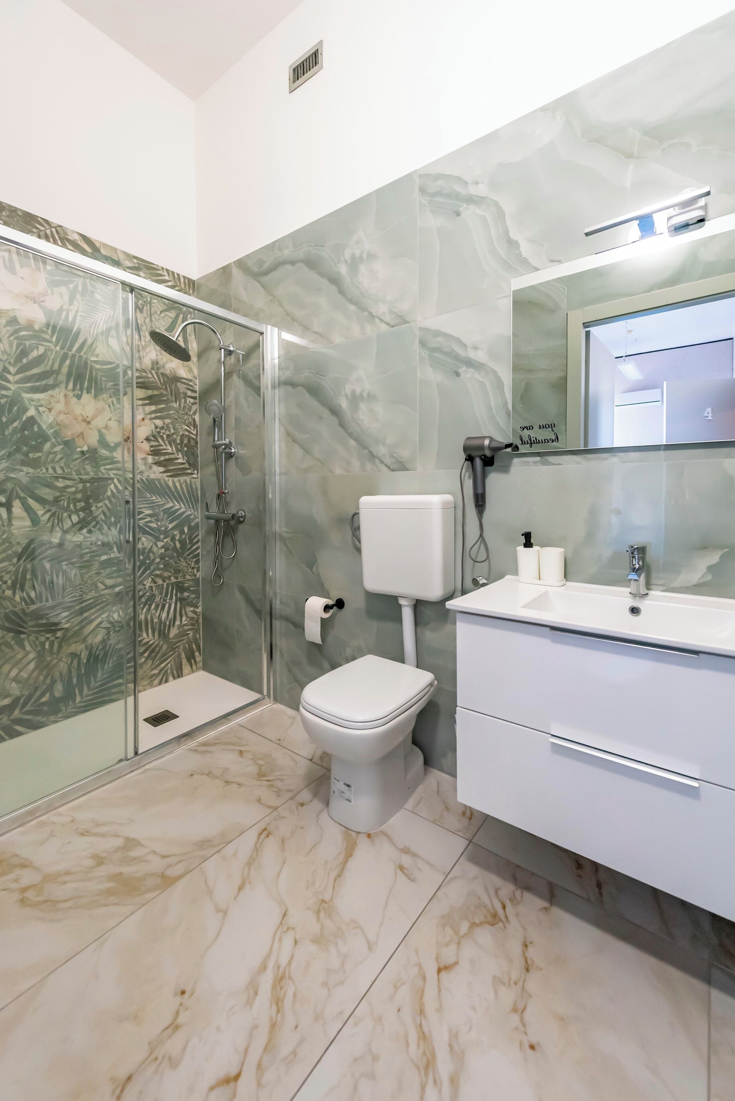 A bathroom with a glass-enclosed shower, a toilet, and a vanity with a mirror.