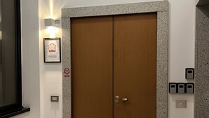 Une chambre d’hôtel avec une porte à deux battants, un certificat encadré accroché au mur et un luminaire au-dessus de la porte.