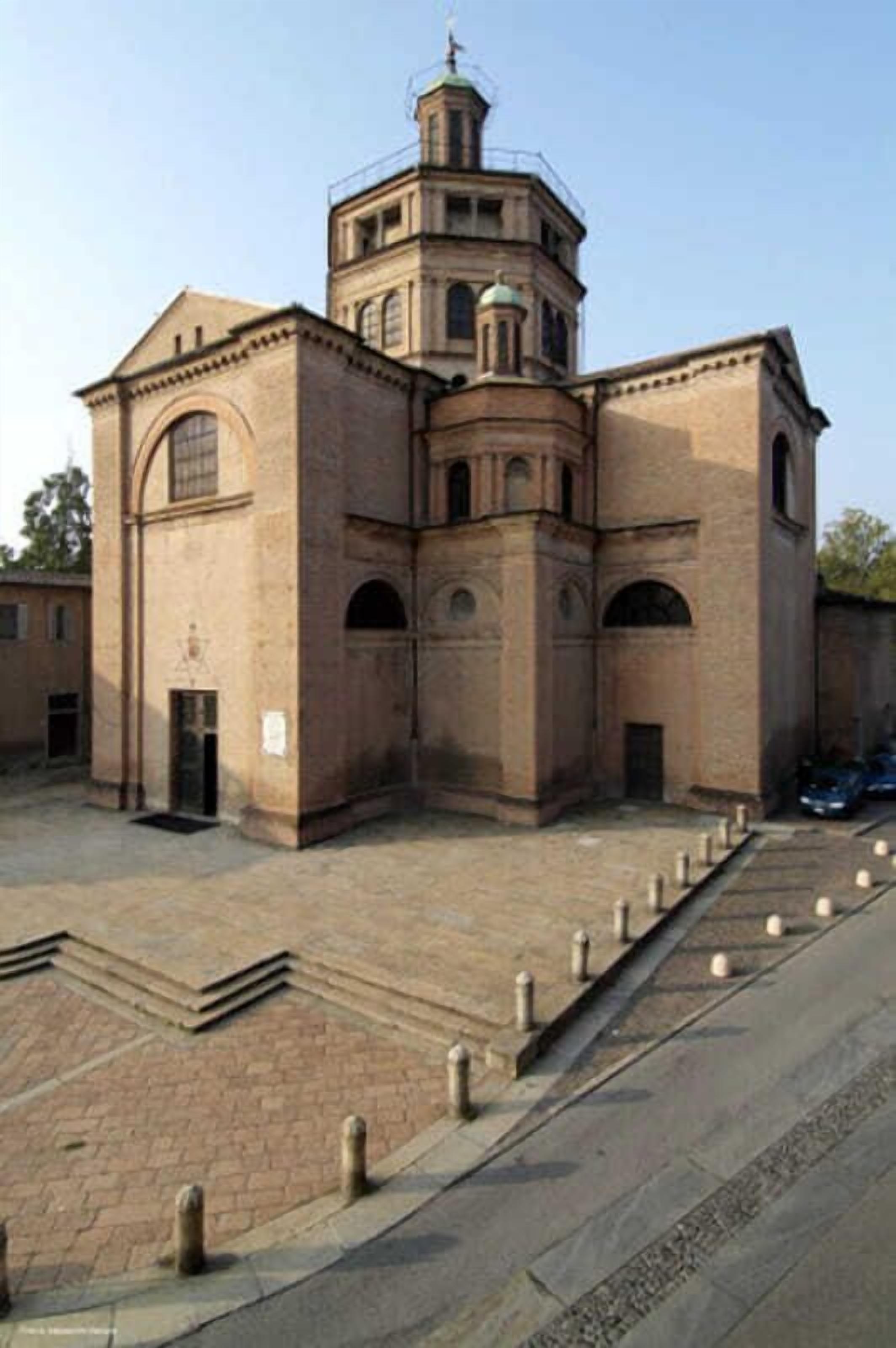 Un edificio histórico con una torre central, ventanas de arco y un patio empedrado.