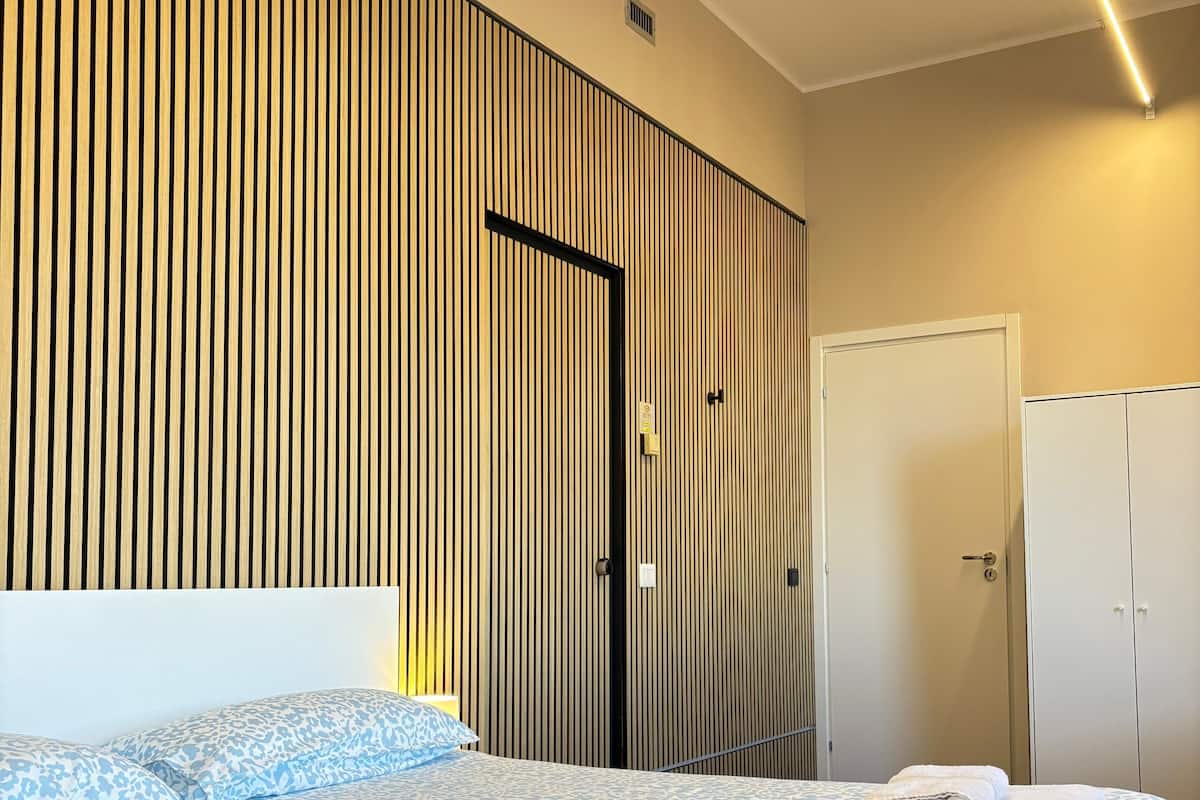 A modern bedroom with a bed, a wardrobe, and a door.