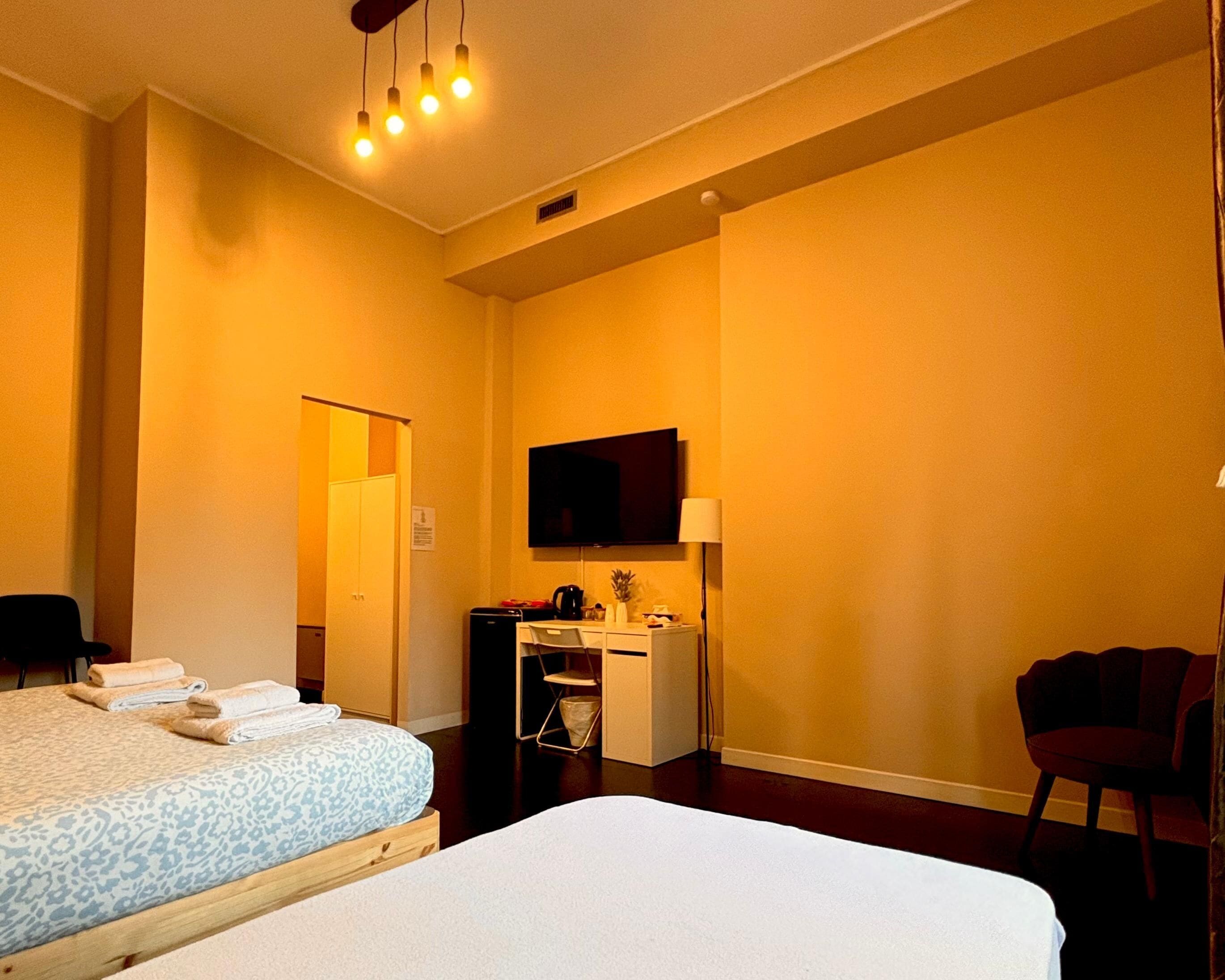 A hotel room with two beds, a desk, a television, and a chair.