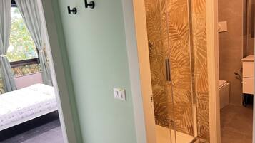A room with a bed, a shower with a palm leaf pattern, and a toilet.