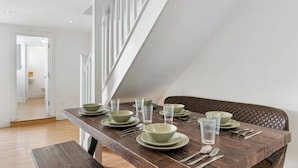 A dining area with a wooden table set for four, equipped with green plates, bowls, and clear glasses. - Group & Contractor-Friendly 4Bed House (Brighton and Hove)
