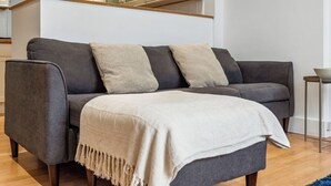 A modern living room with a grey sofa, two beige throw pillows, and a white throw blanket. - Group & Contractor-Friendly 4Bed House (Brighton and Hove)