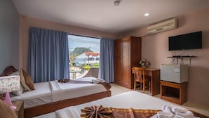 Ett hotellrum med två sängar, ett skrivbord, en stol, en TV och en luftkonditioneringsanläggning.