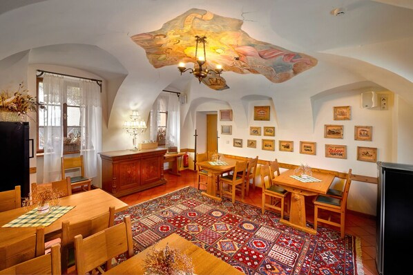Un comedor con una mesa y sillas de madera, un tapete estampado y un mural en el techo.