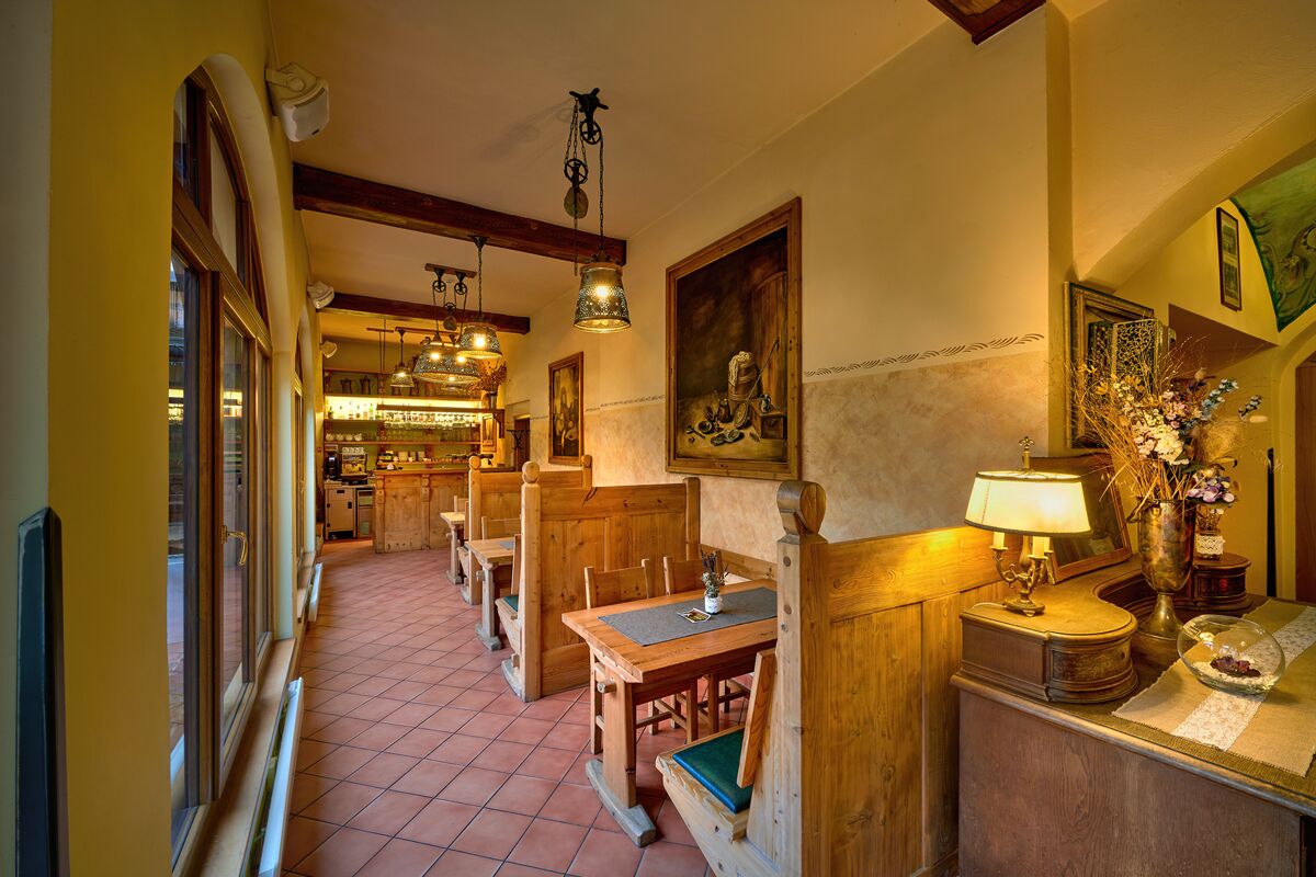 A cozy restaurant with wooden booths and tables, a tiled floor, and hanging lights.