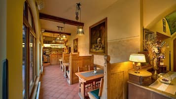 A cozy restaurant with wooden booths and tables, a tiled floor, and hanging lights.