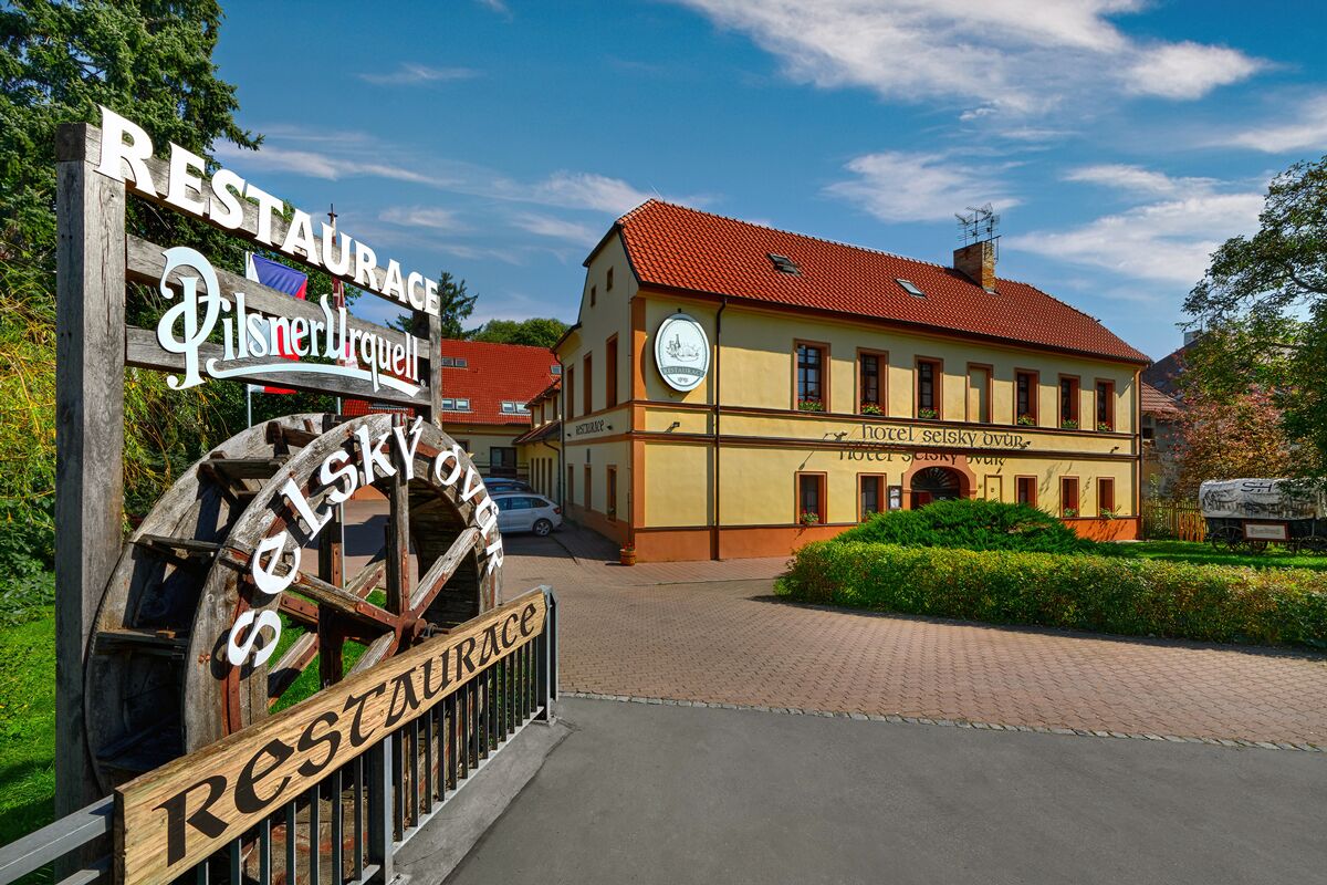 Un edificio tradizionale con un cartello che indica 'Pilsner Urquell' e 'Hotel Sejsky ovnice'.