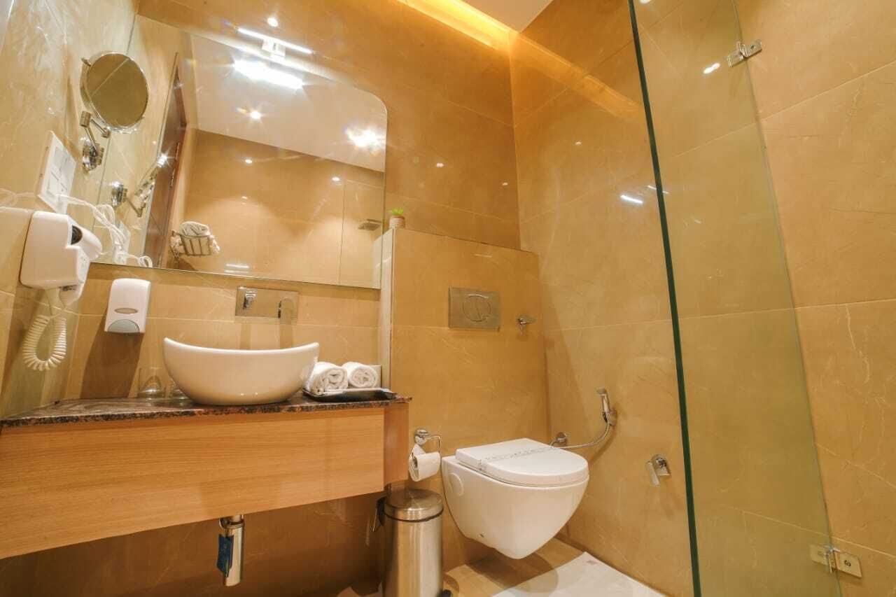 Un baño moderno con un lavamanos grande, inodoro y ducha con mampara de vidrio.