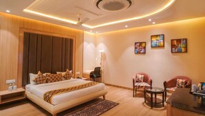 A modern hotel room with a large bed, a desk, two chairs, and a ceiling light fixture. - PSK Pride by BDS Hotels (Amritsar)
