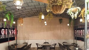 An outdoor dining area with wicker furniture and hanging plants. - PSK Pride by BDS Hotels (Amritsar)
